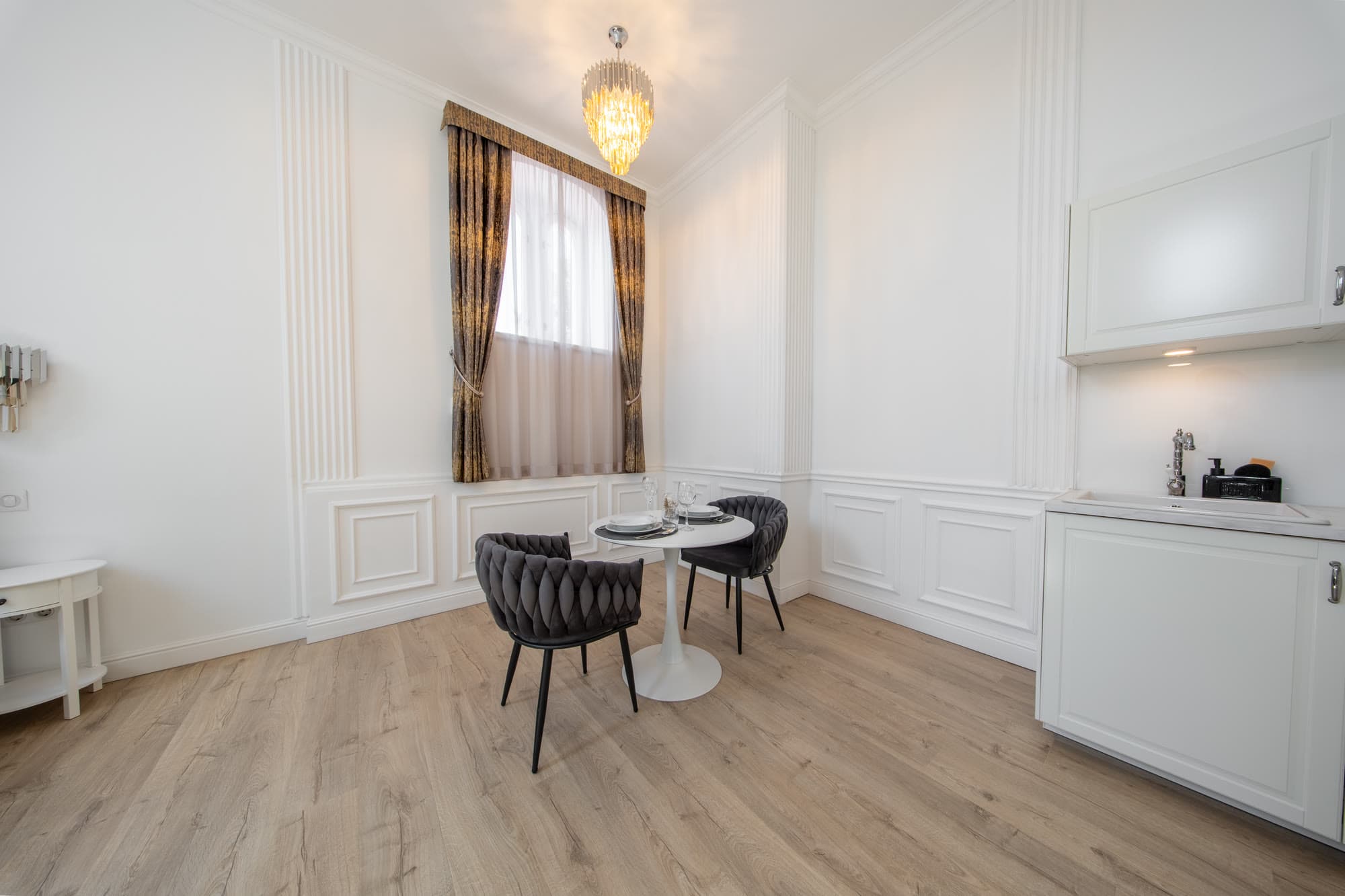 Az apartman nappalija kerek étkezőasztallal és hűtővel.