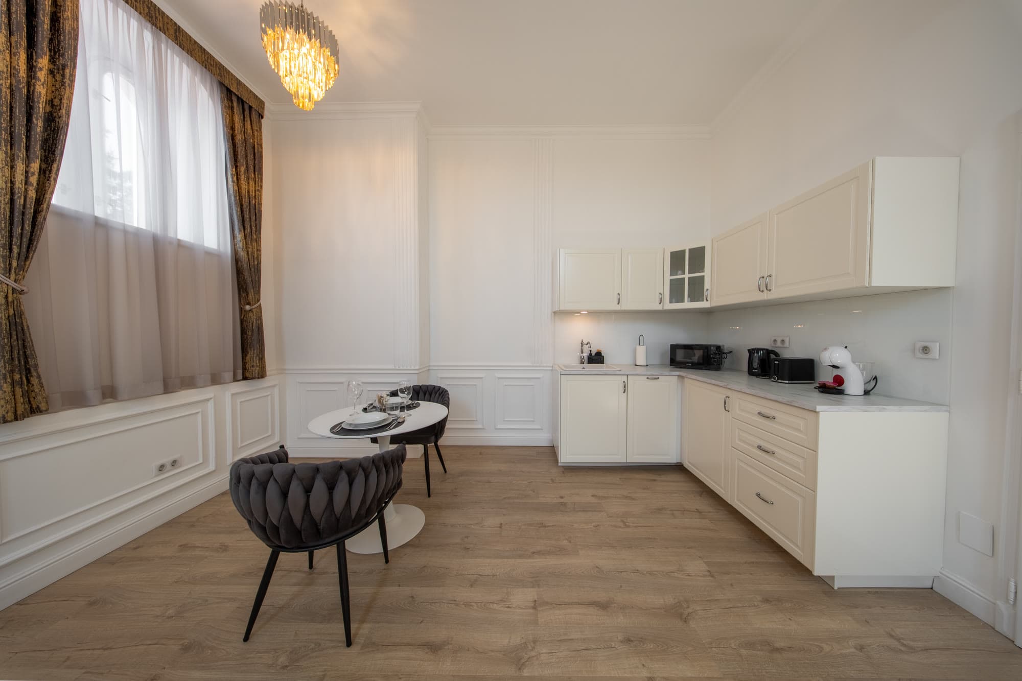 Az apartman konyhasarka és étkezőasztala a függönyös ablaknál.